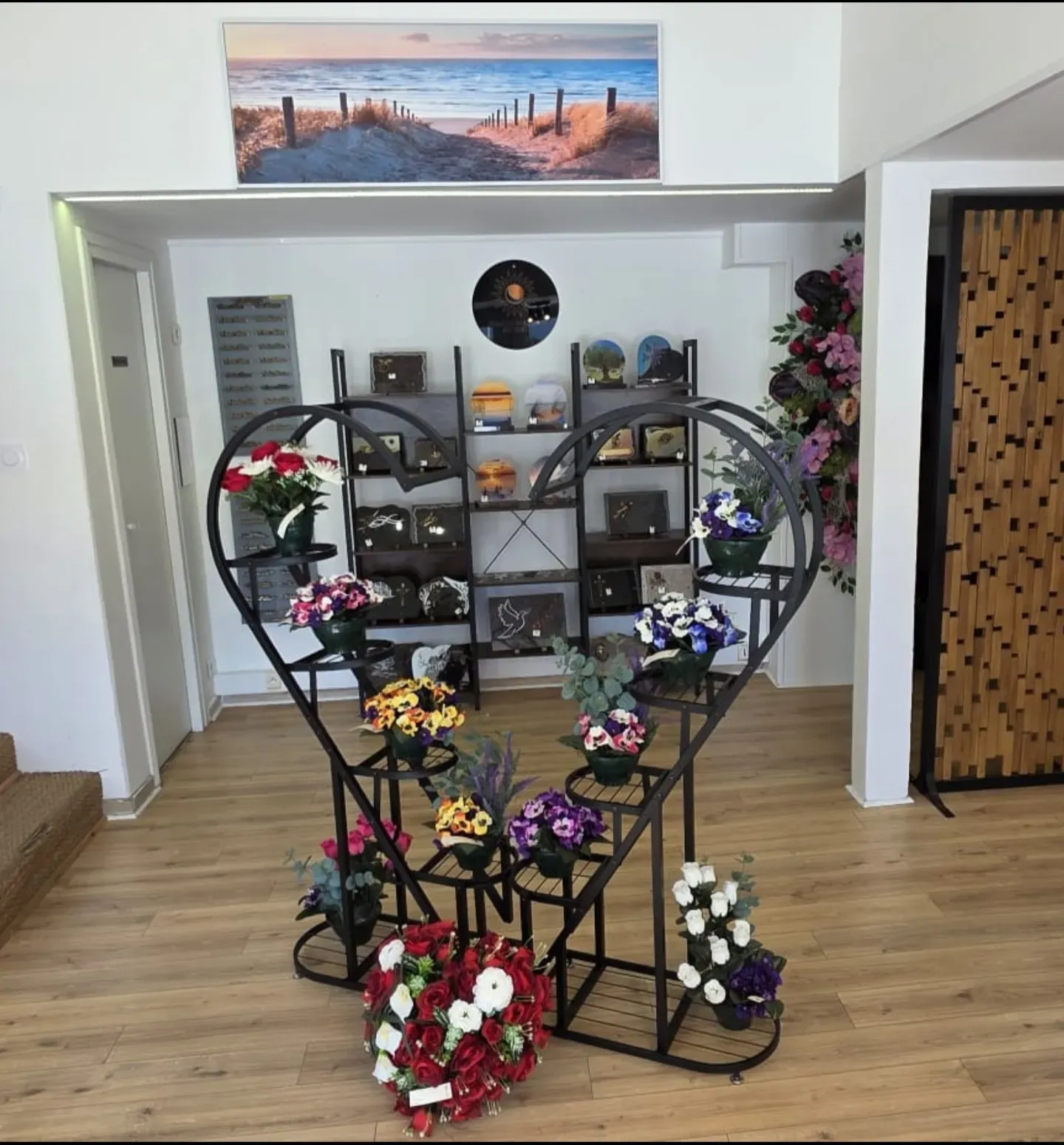 Exposition de fleurs artificielles et de plaques funéraires dans une boutique de pompes funèbres.